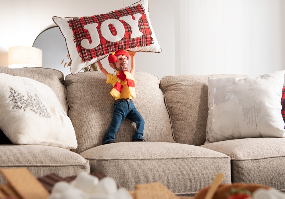 Little Bob Holding a "Joy" Pillow above his head.