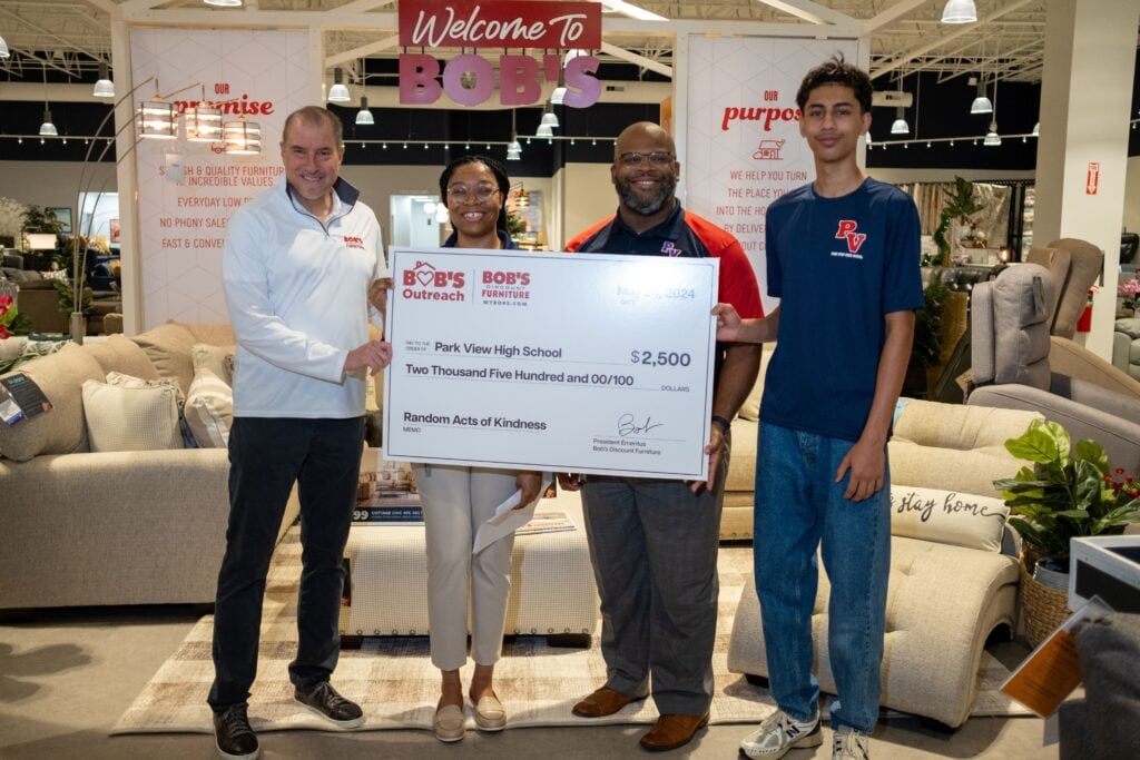 Bob’s Discount Furniture presented a $2,500 Random Acts of Kindness donation to Park View High School, representing their commitment to supporting local schools. Principal Jason Jefferson (center, right) of Park View High School accepted the donation alongside student, Subhan Gillani (right) presented by Store Manager, Nicole Evans (center, left) and Roger Dunlap (left), Senior Vice President of Retail for Bob’s Discount Furniture.